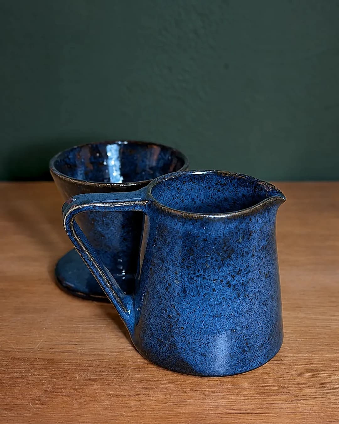 Conjunto coador de café e jarra, em cerâmica feita à mão por Pauliria Queiroz, sobre a prateleira do ateliê